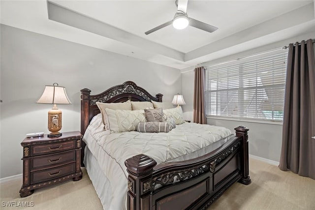 carpeted bedroom with ceiling fan and a raised ceiling