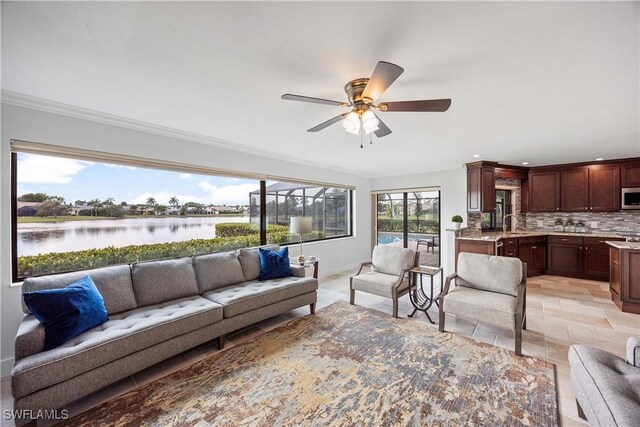 living room featuring a water view, ceiling fan, ornamental molding, and sink