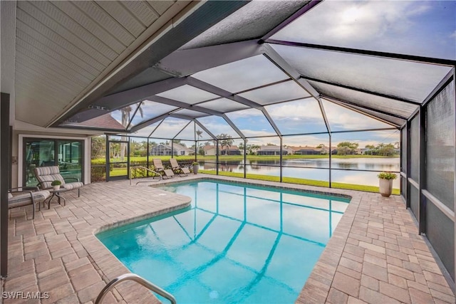 view of pool featuring glass enclosure, a water view, and a patio