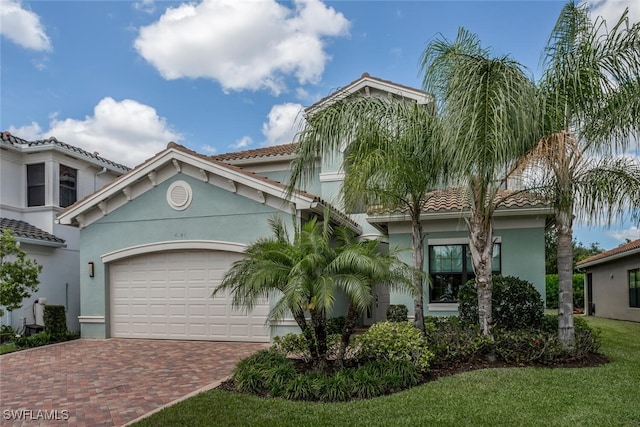 mediterranean / spanish home with a garage and a front lawn