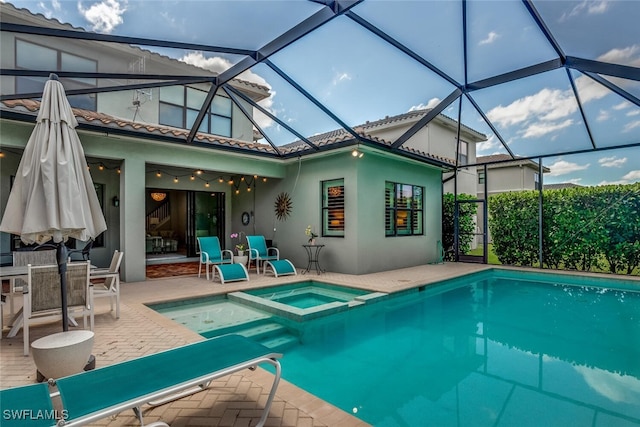 view of pool featuring glass enclosure, an in ground hot tub, and a patio