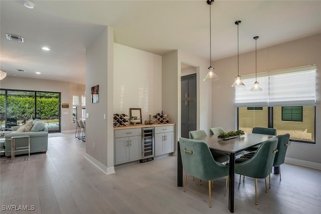 dining space featuring light hardwood / wood-style flooring, beverage cooler, and indoor bar