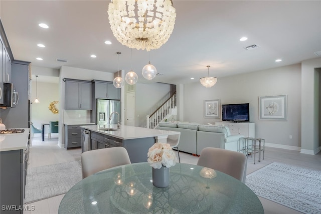 dining room with light wood-type flooring, a notable chandelier, and sink