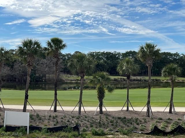surrounding community with a water view, view of golf course, and a lawn