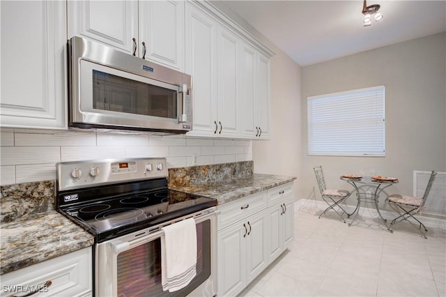 kitchen with appliances with stainless steel finishes, tasteful backsplash, light stone counters, white cabinets, and light tile patterned flooring