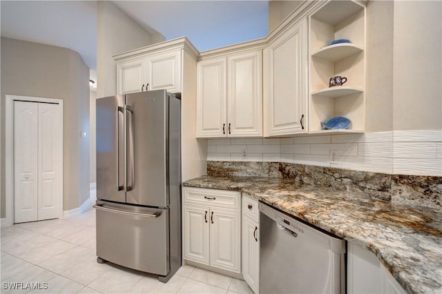 kitchen featuring decorative backsplash, dark stone countertops, light tile patterned floors, and stainless steel appliances