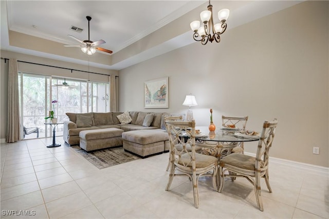 living room with ceiling fan with notable chandelier, light tile patterned floors, ornamental molding, and a tray ceiling