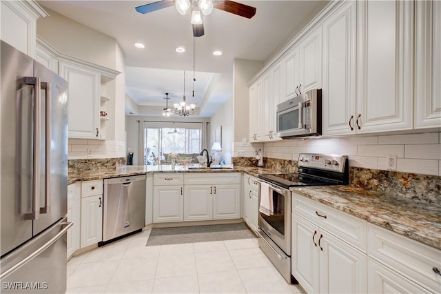 kitchen featuring decorative backsplash, appliances with stainless steel finishes, decorative light fixtures, dark stone countertops, and white cabinets