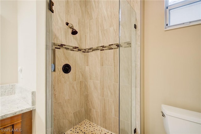 bathroom featuring vanity, toilet, and a tile shower