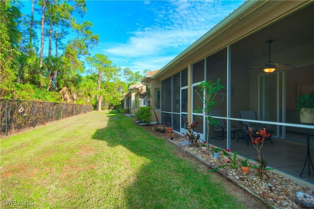 view of yard with a sunroom, ceiling fan, and a patio