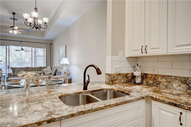 kitchen featuring white cabinetry, light stone counters, sink, and a chandelier