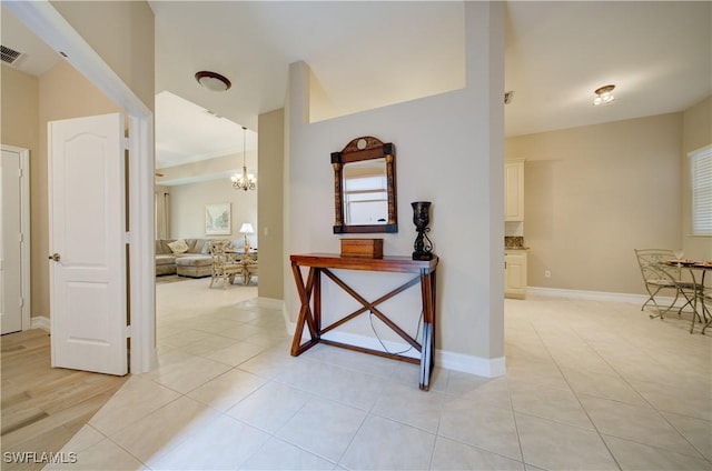 hallway with a chandelier and light tile patterned flooring