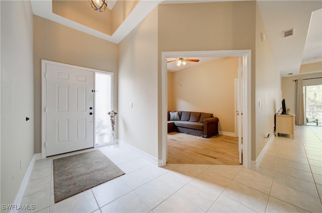 foyer featuring ceiling fan, light tile patterned floors, and a high ceiling