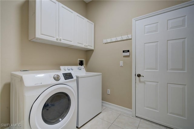 laundry area featuring cabinets, light tile patterned floors, and washer and dryer