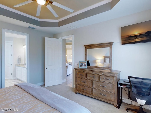 bedroom featuring connected bathroom, ceiling fan, light colored carpet, a tray ceiling, and ornamental molding