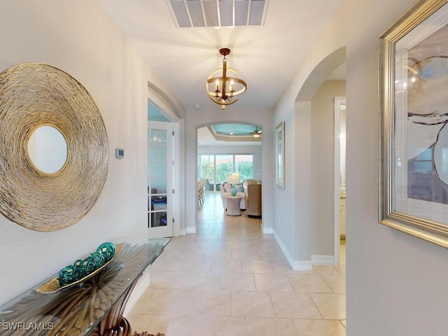 corridor featuring light tile patterned floors and a notable chandelier