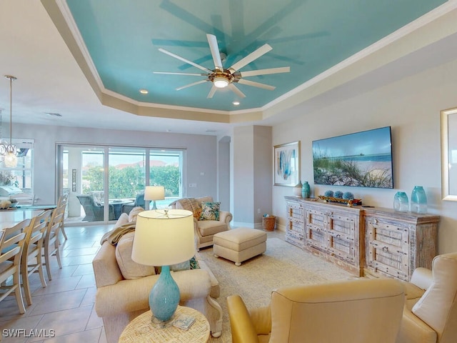 living room featuring ceiling fan, light tile patterned floors, crown molding, and a tray ceiling