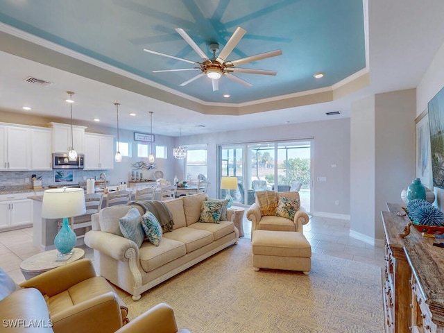 living room featuring ceiling fan, a raised ceiling, light tile patterned floors, and crown molding