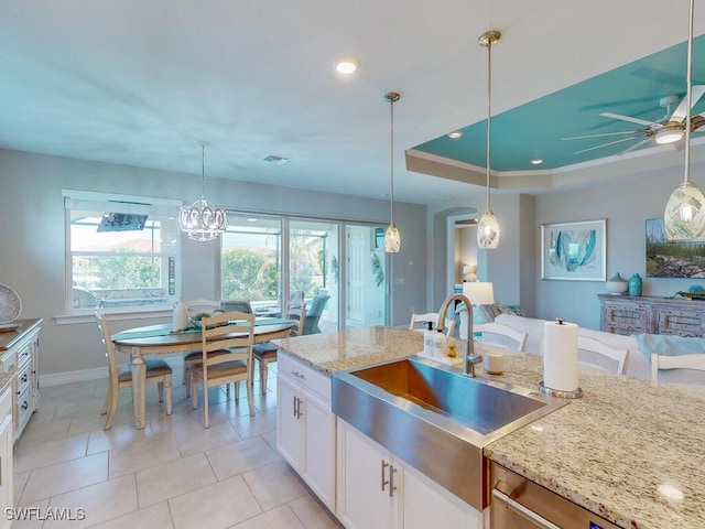 kitchen featuring hanging light fixtures, white cabinetry, sink, and light stone counters