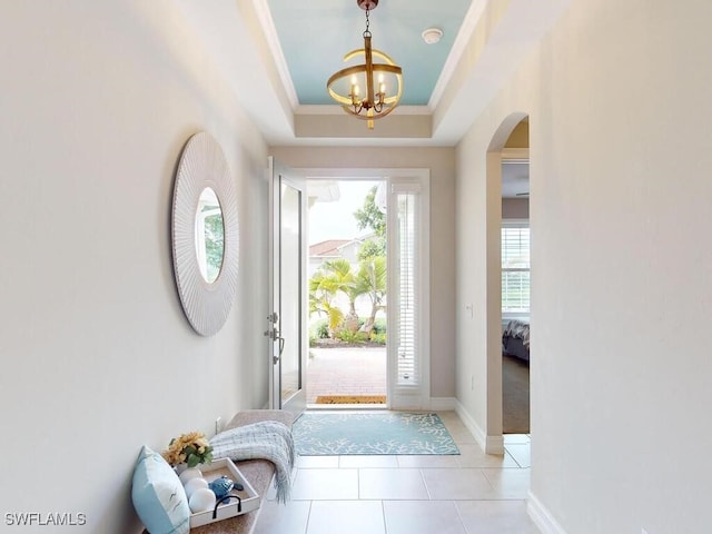 foyer featuring a chandelier, a raised ceiling, ornamental molding, and light tile patterned flooring