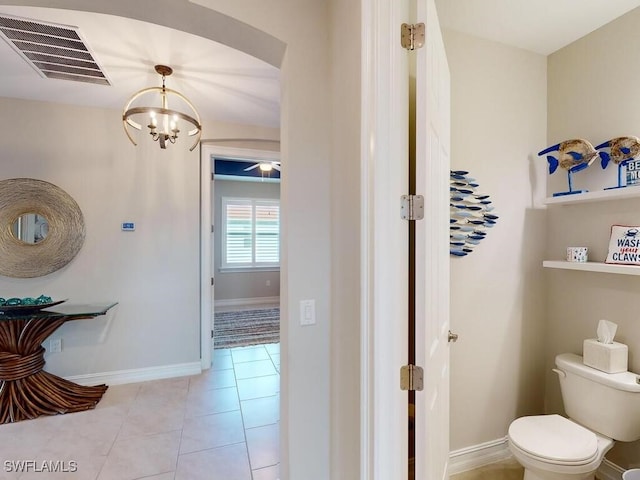 bathroom with tile patterned flooring, a chandelier, and toilet