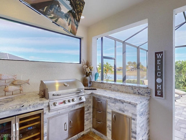 view of patio / terrace featuring a water view, sink, area for grilling, exterior kitchen, and beverage cooler