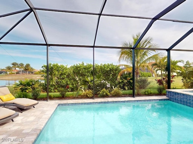 view of pool with glass enclosure, a patio area, and a water view