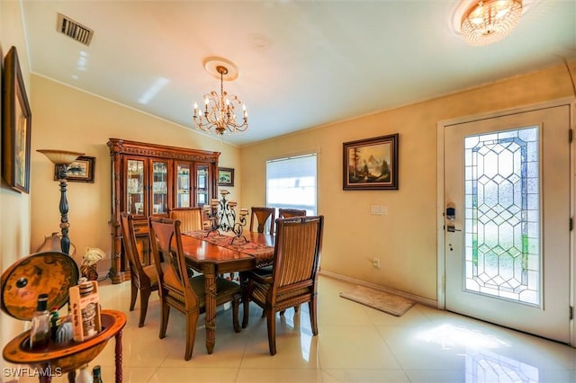 tiled dining space with lofted ceiling and an inviting chandelier