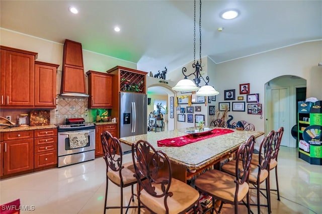 kitchen with stainless steel appliances, tasteful backsplash, premium range hood, decorative light fixtures, and light tile patterned floors