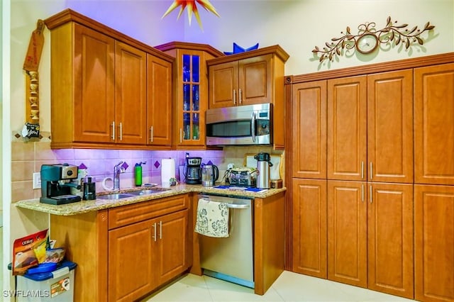 kitchen with decorative backsplash, sink, light stone countertops, and stainless steel appliances