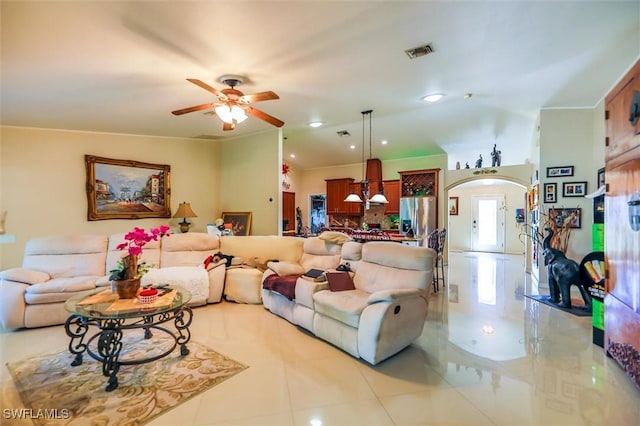 tiled living room with ceiling fan and crown molding