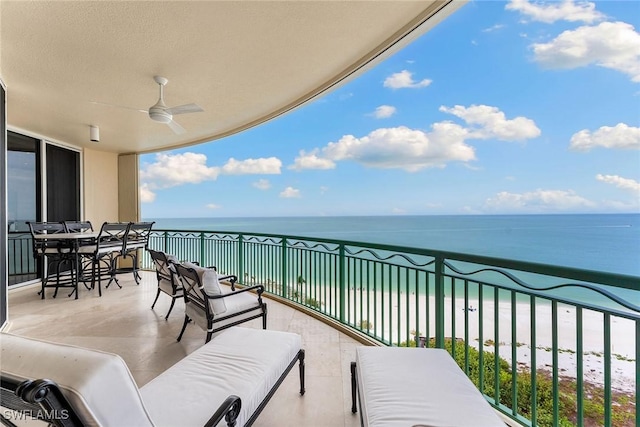 balcony featuring a water view, a beach view, and ceiling fan