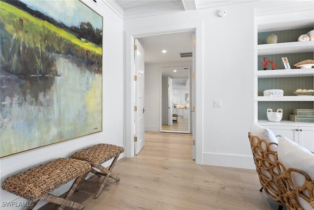 hallway with built in shelves and light hardwood / wood-style flooring