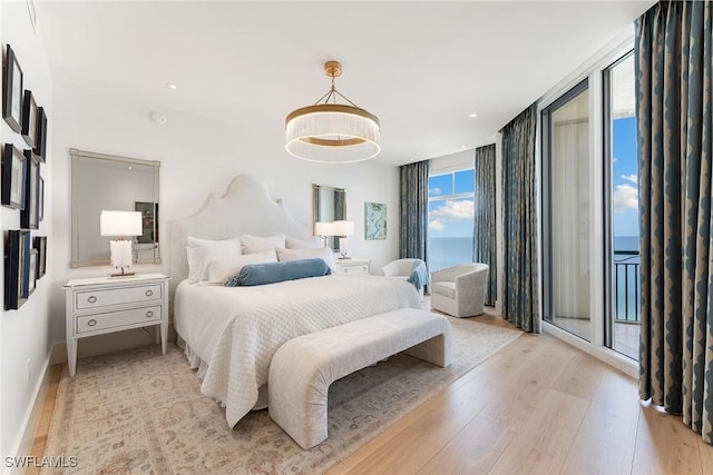 bedroom with access to outside, light wood-type flooring, expansive windows, and a water view