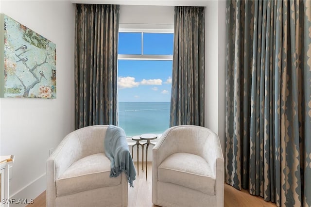 sitting room featuring light hardwood / wood-style floors and a water view