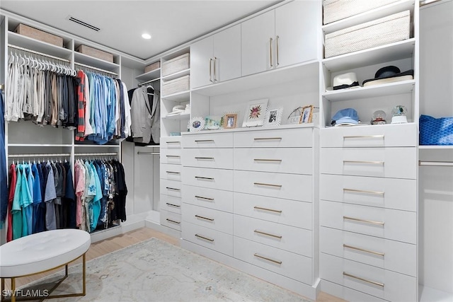 walk in closet with light hardwood / wood-style floors