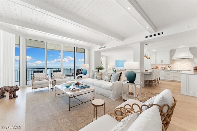 living room with floor to ceiling windows, beamed ceiling, a water view, and light hardwood / wood-style floors