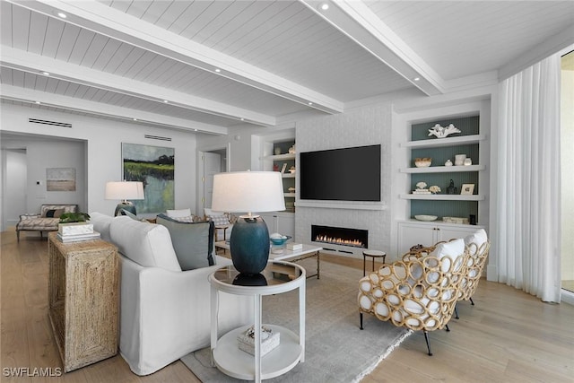 living room featuring a brick fireplace, light wood-type flooring, built in features, and beam ceiling