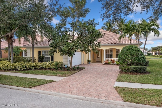 mediterranean / spanish house with a porch, a garage, and a front lawn