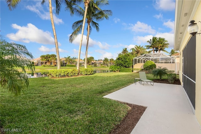 view of yard featuring glass enclosure, a water view, and a patio