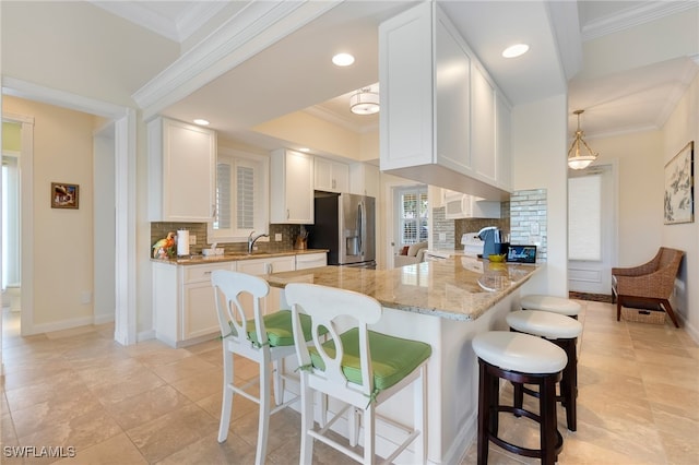 kitchen with white cabinets, decorative backsplash, stainless steel fridge with ice dispenser, and kitchen peninsula