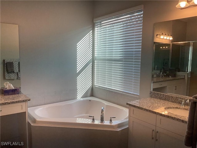 bathroom with vanity and a relaxing tiled tub