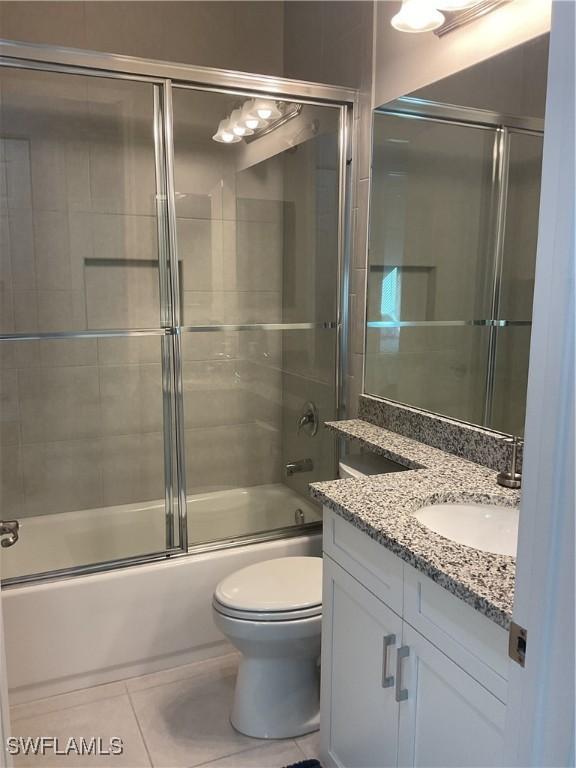 full bathroom featuring tile patterned flooring, vanity, toilet, and enclosed tub / shower combo