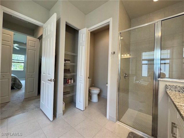 ensuite bathroom featuring a stall shower, toilet, and tile patterned flooring