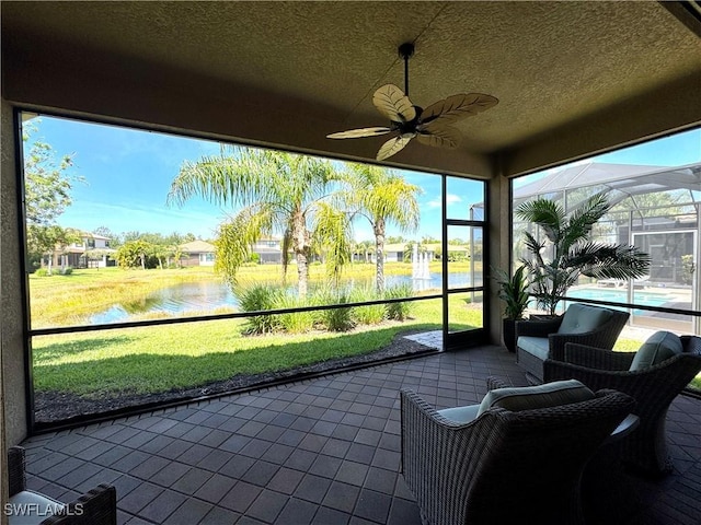 sunroom / solarium with ceiling fan and a water view