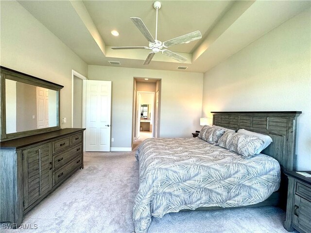 bedroom with visible vents, light carpet, and a tray ceiling