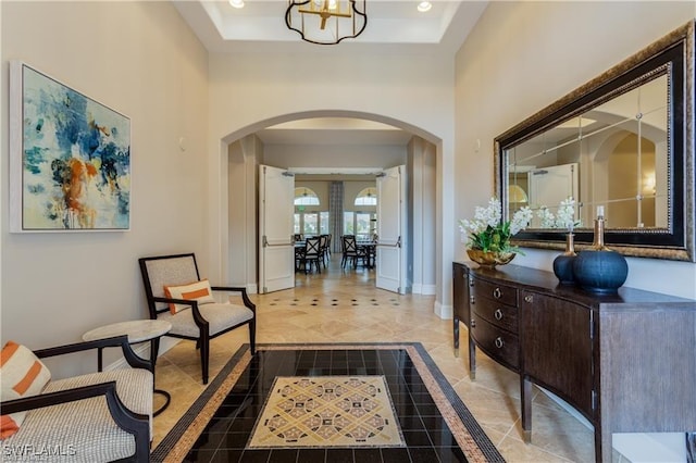 foyer with a raised ceiling and an inviting chandelier