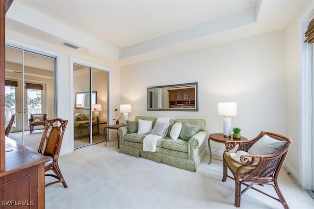 carpeted living room with a raised ceiling and french doors