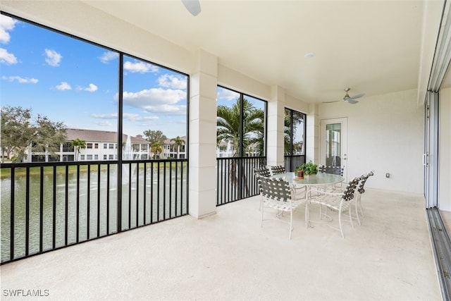 sunroom / solarium featuring ceiling fan and a water view