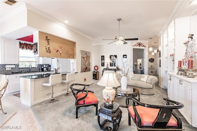 tiled living room with ceiling fan, crown molding, and sink